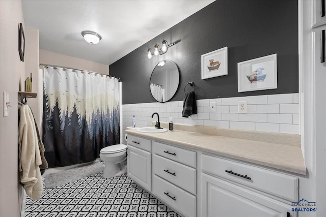19329 US Highway 85, Belle Fourche, SD 57717 - bathroom with a wainscoted wall, tile patterned floors, toilet, vanity, and tile walls