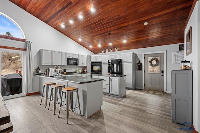 19329 US Highway 85, Belle Fourche, SD 57717 - kitchen with a sink, light wood finished floors, a peninsula, dark countertops, and black appliances