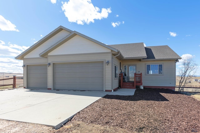 ranch-style house featuring roof with shingles, concrete driveway, a garage, and fence
