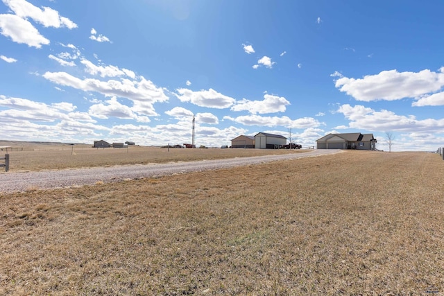 view of yard with driveway, an outbuilding, an outdoor structure, a carport, and a rural view