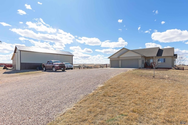 view of front of home featuring an outbuilding, gravel driveway, a front yard, and an attached garage