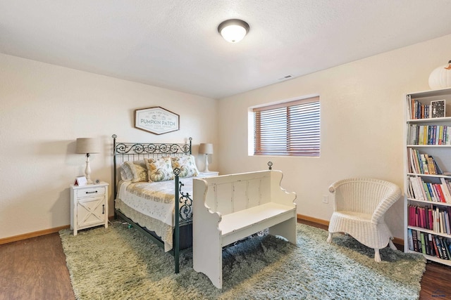 bedroom featuring baseboards, visible vents, wood finished floors, and a textured ceiling