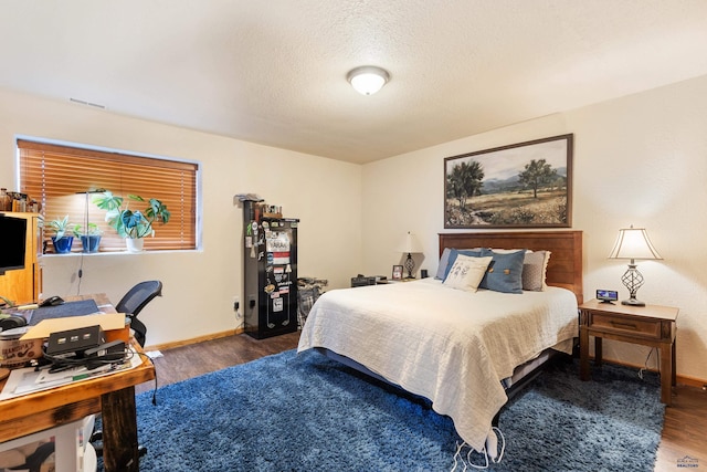 bedroom with a textured ceiling, baseboards, and wood finished floors