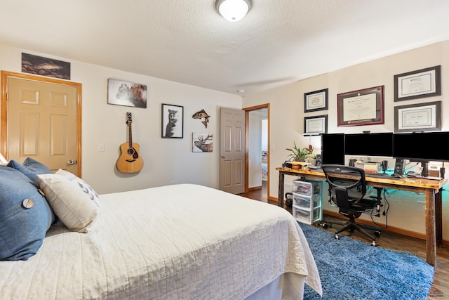 bedroom featuring baseboards, a textured ceiling, and wood finished floors