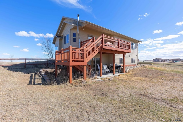 back of house with a fenced backyard, stairs, a wooden deck, and a patio area