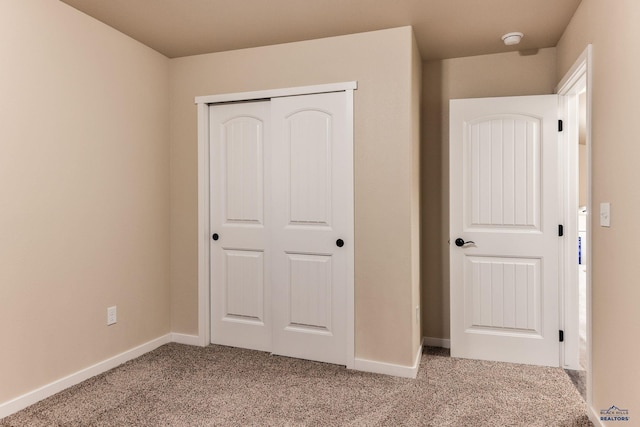 unfurnished bedroom featuring light carpet, a closet, and baseboards