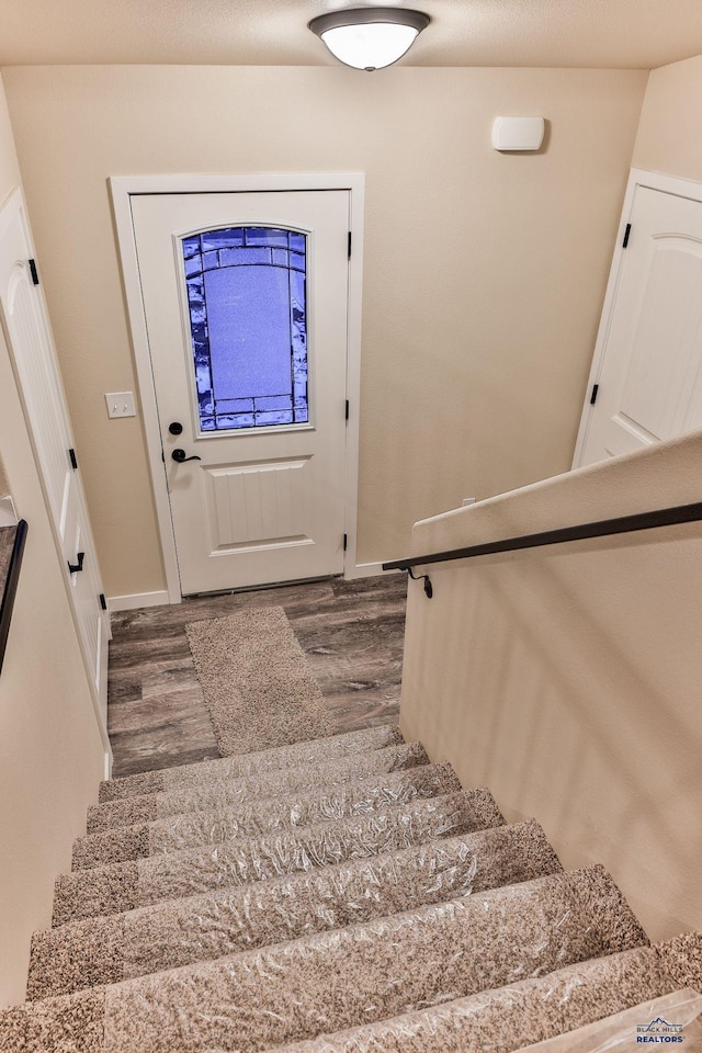 staircase featuring baseboards and wood finished floors