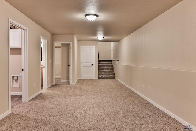 unfurnished room featuring light carpet, stairway, and baseboards