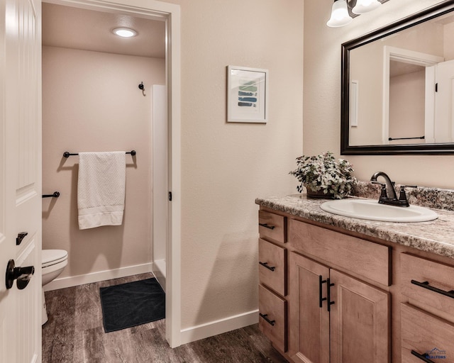 bathroom featuring vanity, baseboards, toilet, and wood finished floors