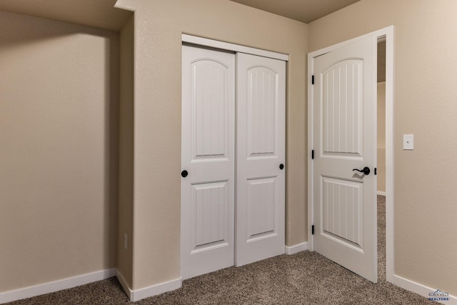 interior space with a closet, baseboards, and dark colored carpet