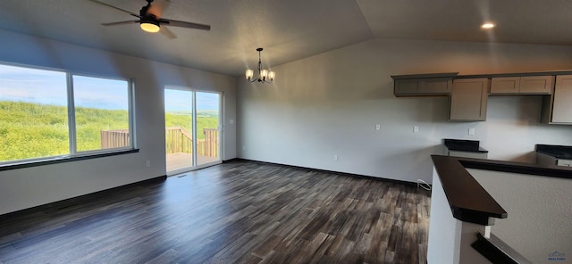 unfurnished dining area with baseboards, recessed lighting, dark wood-type flooring, lofted ceiling, and ceiling fan with notable chandelier