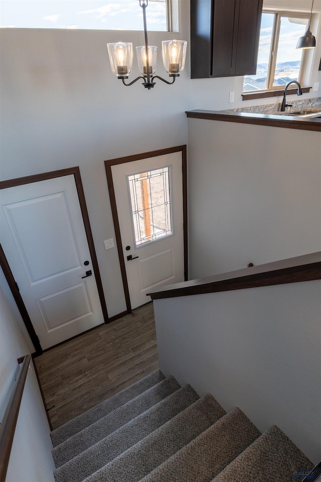 stairway featuring wood finished floors and an inviting chandelier