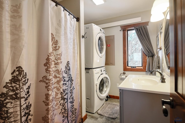 washroom featuring a sink, stacked washer / dryer, laundry area, and baseboards