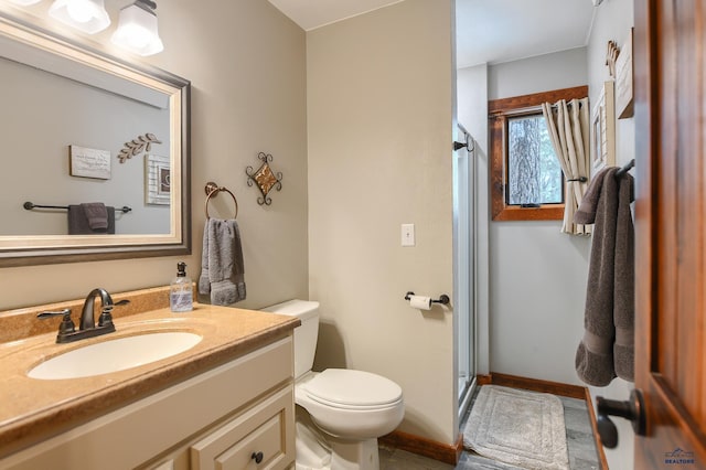 bathroom with baseboards, toilet, a stall shower, and vanity