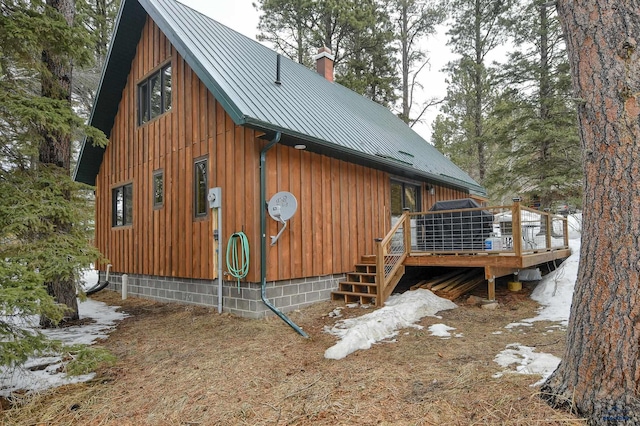 view of home's exterior featuring a chimney, metal roof, and a wooden deck