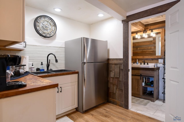kitchen featuring dark countertops, white cabinets, a sink, and freestanding refrigerator