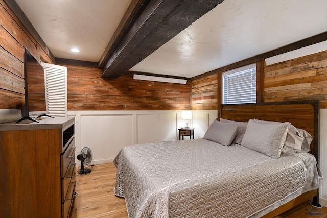bedroom with light wood-style flooring and beam ceiling