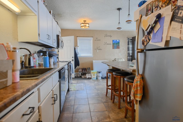 kitchen featuring a sink, white cabinets, appliances with stainless steel finishes, and a textured ceiling