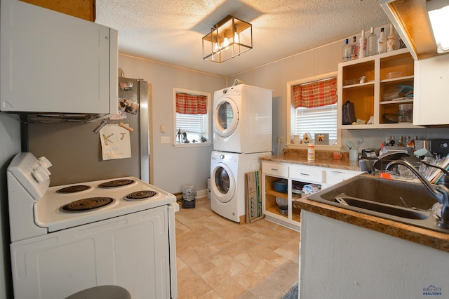 kitchen featuring white range with electric cooktop, a sink, stacked washing maching and dryer, and a wealth of natural light