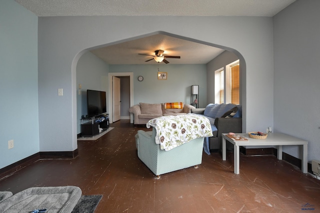 living area with arched walkways, ceiling fan, baseboards, and wood finished floors