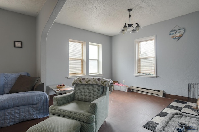 living area featuring a textured ceiling, baseboard heating, wood finished floors, and a chandelier