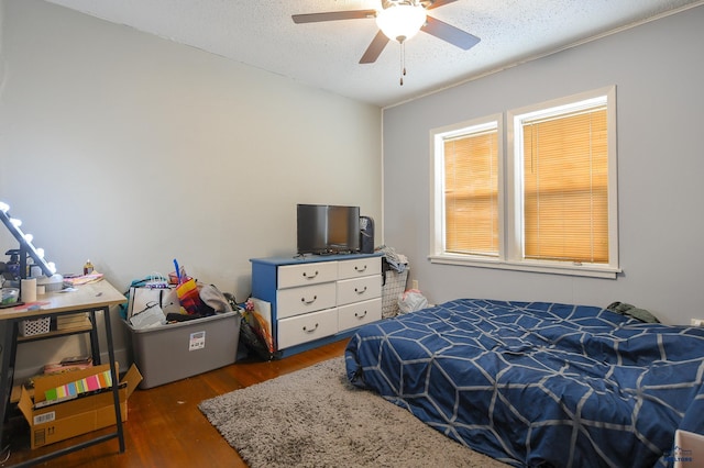 bedroom featuring a textured ceiling, ceiling fan, and wood finished floors