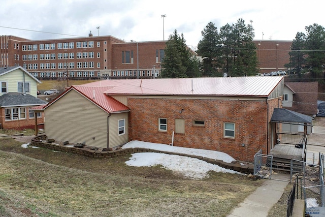 exterior space featuring metal roof, fence, and brick siding