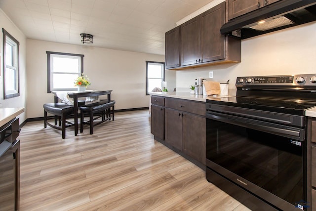 1920 Reservoir Rd, Rapid City, SD 57703 - kitchen featuring light countertops, light wood-type flooring, under cabinet range hood, stainless steel electric stove, and dark brown cabinets