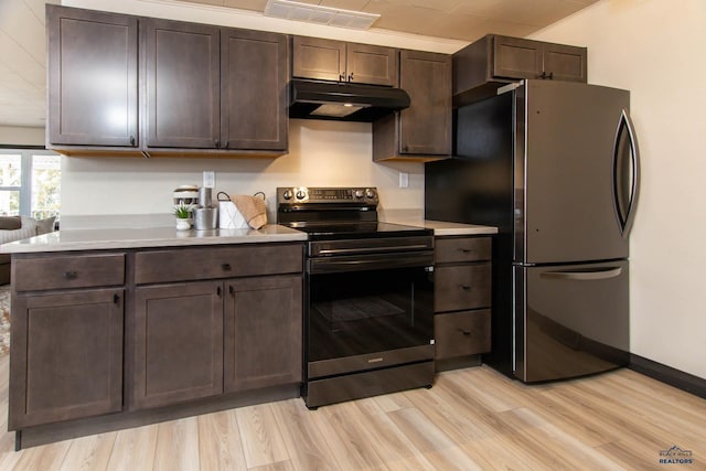 1920 Reservoir Rd, Rapid City, SD 57703 - kitchen with visible vents, under cabinet range hood, black electric range oven, light wood-style floors, and freestanding refrigerator