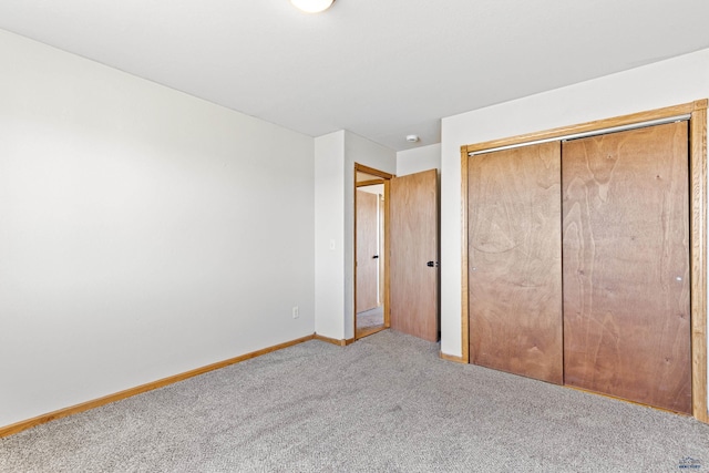unfurnished bedroom with baseboards, carpet flooring, and a closet
