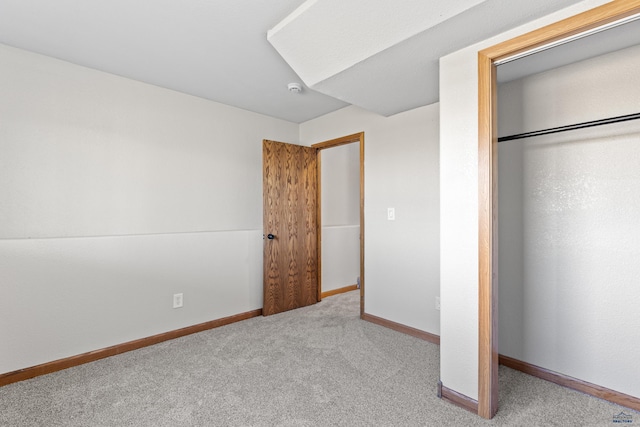 unfurnished bedroom with a closet, carpet floors, and baseboards