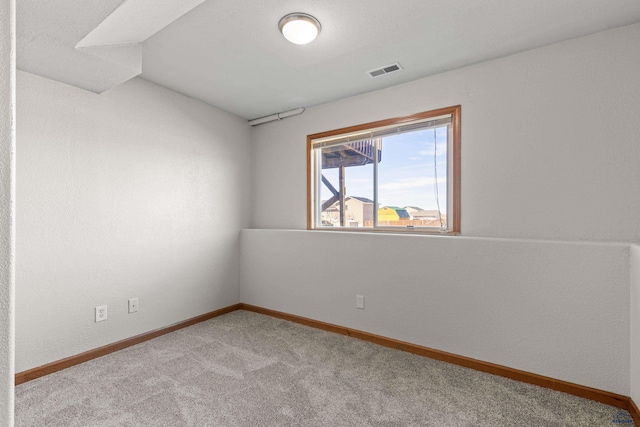 carpeted empty room featuring baseboards and visible vents