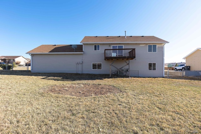 rear view of property with a balcony, fence, and a yard