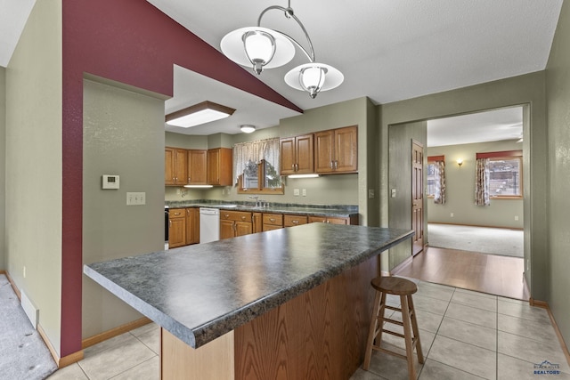 2506 Junction Dr, Rapid City, SD 57702 - kitchen with light tile patterned flooring, a kitchen bar, white dishwasher, and dark countertops