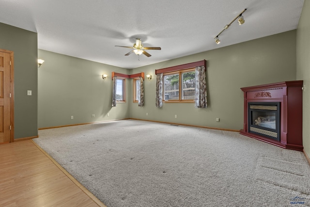 2506 Junction Dr, Rapid City, SD 57702 - unfurnished living room featuring a ceiling fan, a glass covered fireplace, baseboards, and a textured ceiling