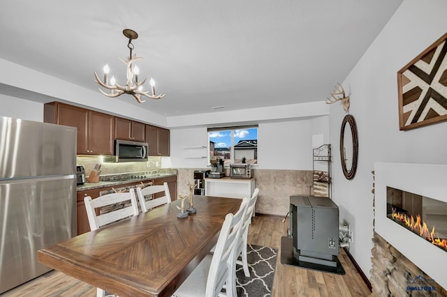 4400 Beringer Dr, Rapid City, SD 57703 - dining room with a glass covered fireplace, light wood-style floors, a chandelier, and a toaster