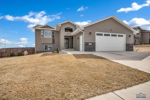 4400 Beringer Dr, Rapid City, SD 57703 - view of front facade with stone siding, concrete driveway, fence, a front lawn, and a garage