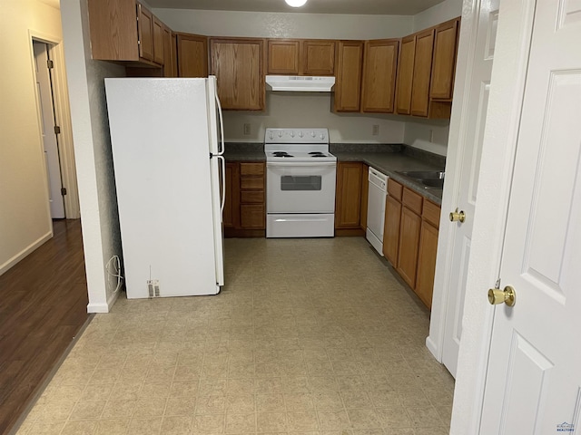 1111 Silver St, Rapid City, SD 57701 - kitchen with white appliances, under cabinet range hood, dark countertops, light floors, and brown cabinets