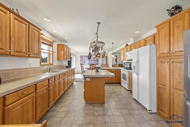 kitchen featuring a kitchen island, light countertops, a sink, and white appliances