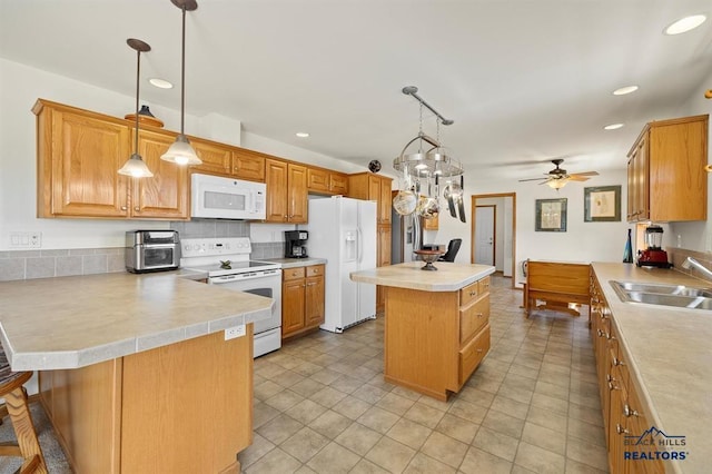kitchen featuring light countertops, a sink, a center island, and white appliances