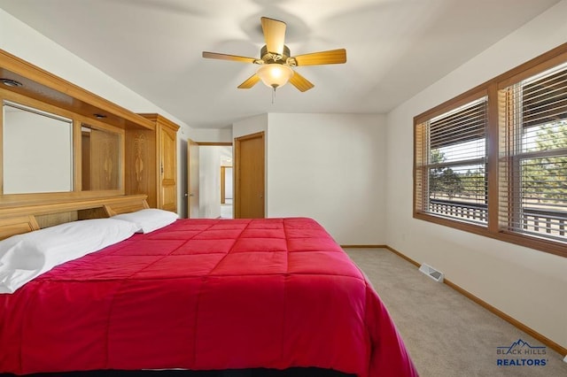 bedroom featuring baseboards, visible vents, a ceiling fan, and light colored carpet