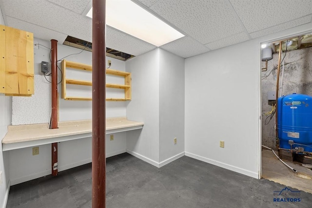 basement with baseboards and a drop ceiling
