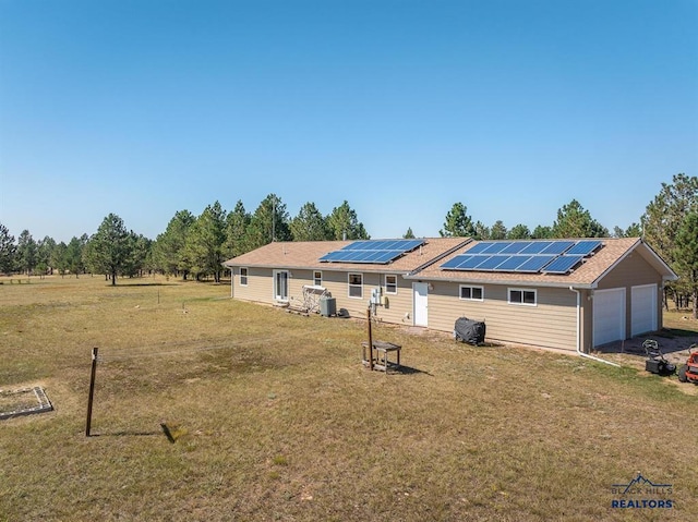 view of front of property featuring a front yard, driveway, a garage, and roof mounted solar panels
