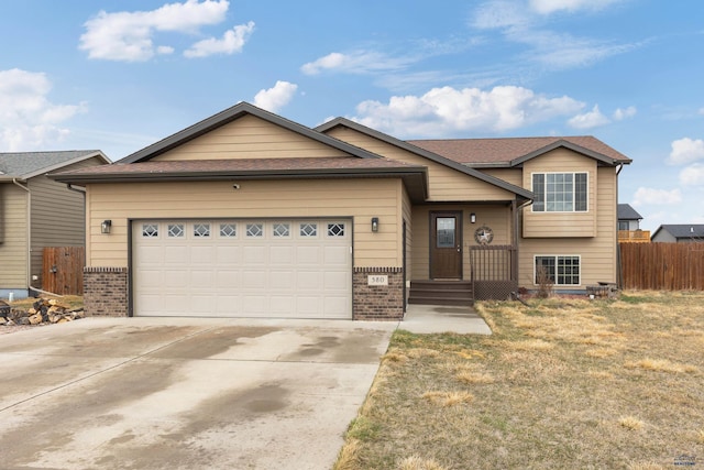 view of front of property featuring driveway, an attached garage, fence, and brick siding