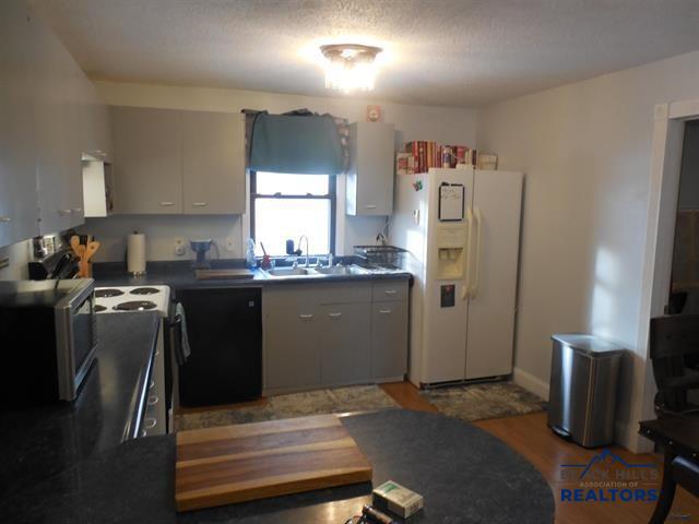 23508 Main St, Caputa, SD 57725 - kitchen featuring white refrigerator with ice dispenser, a sink, stainless steel microwave, dishwashing machine, and dark countertops