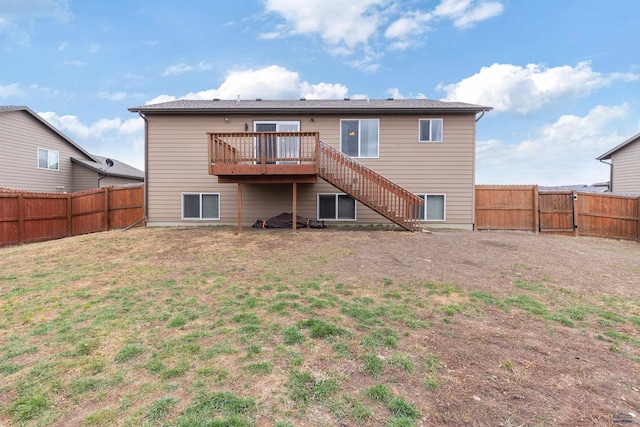 back of property with a gate, a wooden deck, a fenced backyard, stairway, and a lawn