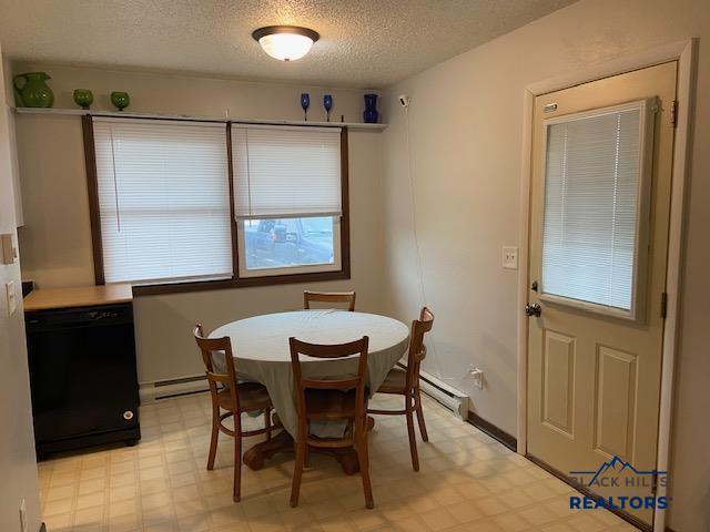 dining area featuring baseboard heating, light floors, and a textured ceiling