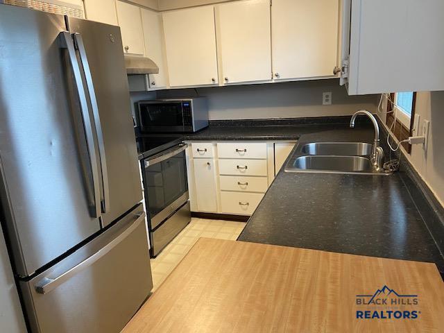 kitchen with under cabinet range hood, white cabinetry, a sink, and stainless steel appliances
