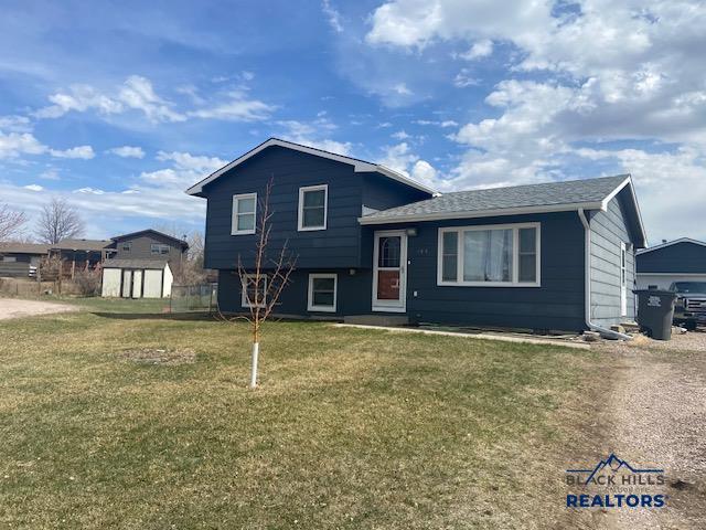 split level home featuring an outbuilding, a front yard, and a storage unit