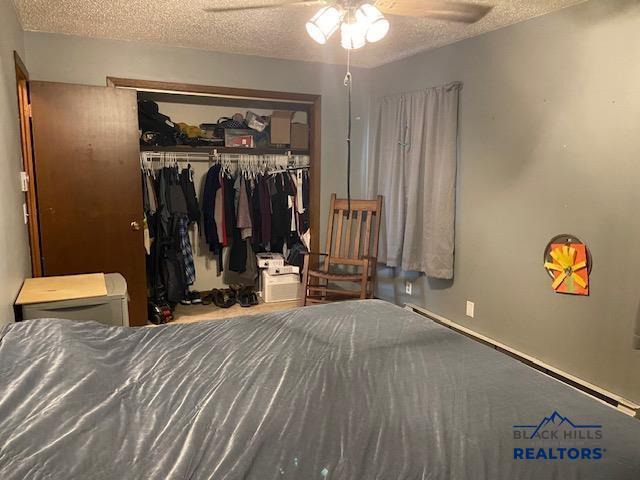 bedroom with a closet, a textured ceiling, and a ceiling fan